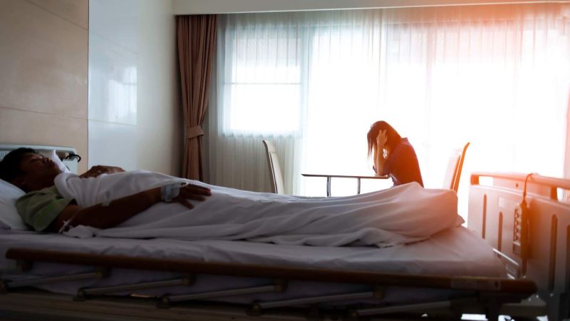 a man laying in a hospital bed next to a woman