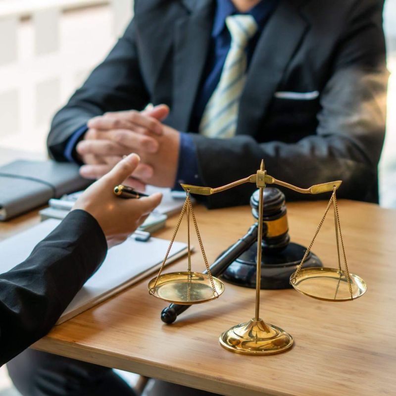 Two people at a table with a scale of justice