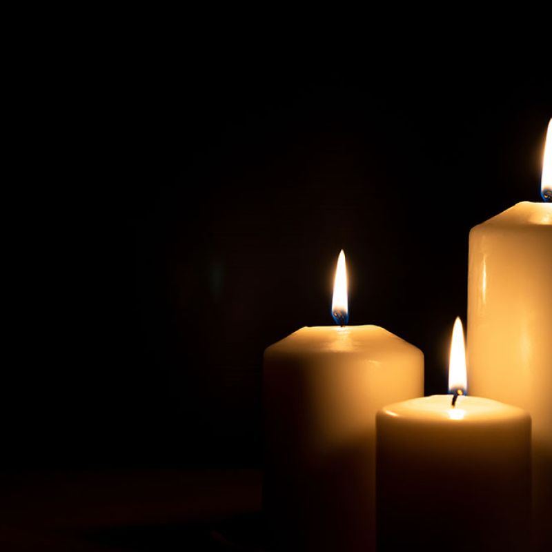 Three lit candles in the dark providing a warm glow, symbolizing tranquility and focus.