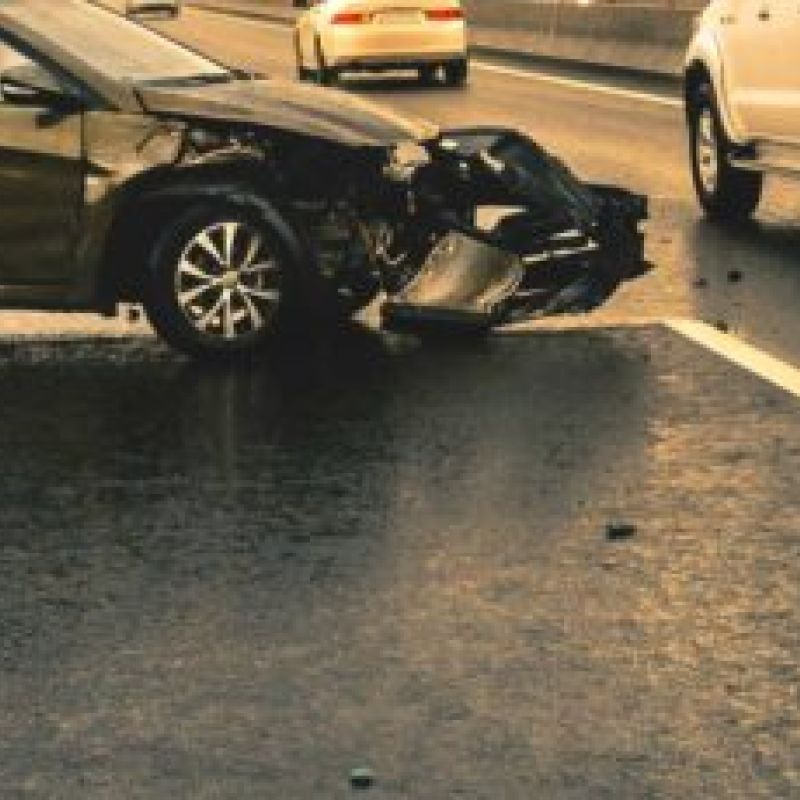 Car accident scene on a highway, showing two vehicles with significant damage on a rainy day.