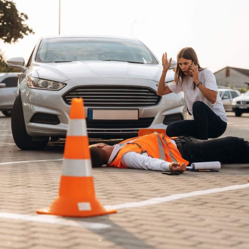 a woman kneeling on the ground next to a man laying on the ground