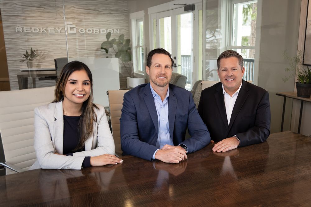 Attorneys from Redkey Gordon Law, wearing suits, are sitting at a conference table in a modern office setting.