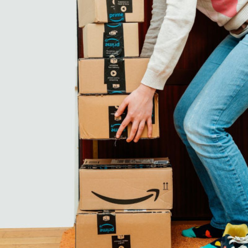 Person stacking Amazon Prime packages inside a closet.