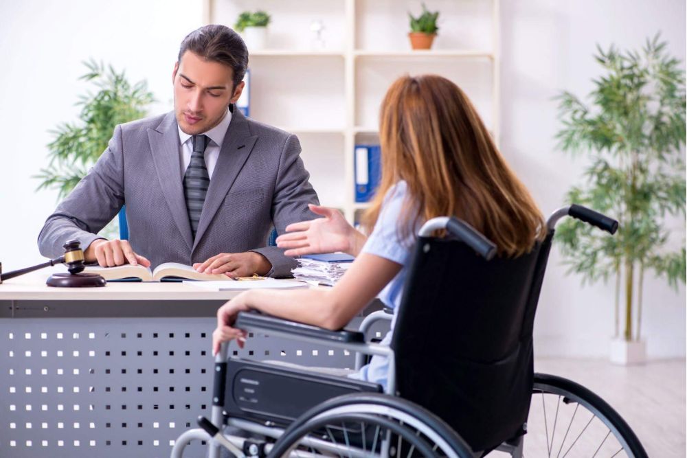 a man in a suit sitting at a desk in front of a woman in a wheelchair