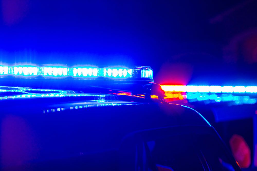 Flashing blue and red police lights on a patrol car at night, symbolizing law enforcement and emergency response.