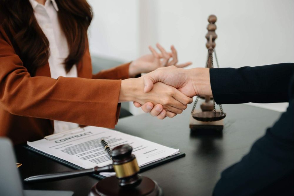 a couple of people shaking hands over a desk