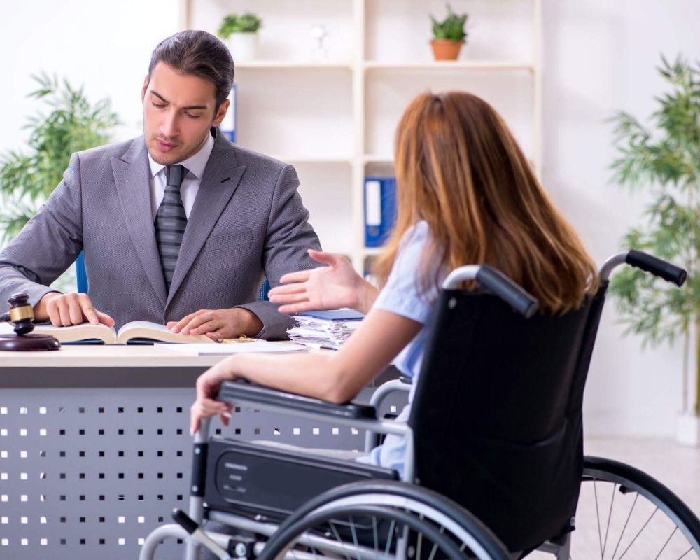 a man in a suit sitting at a desk in front of a woman in a wheelchair