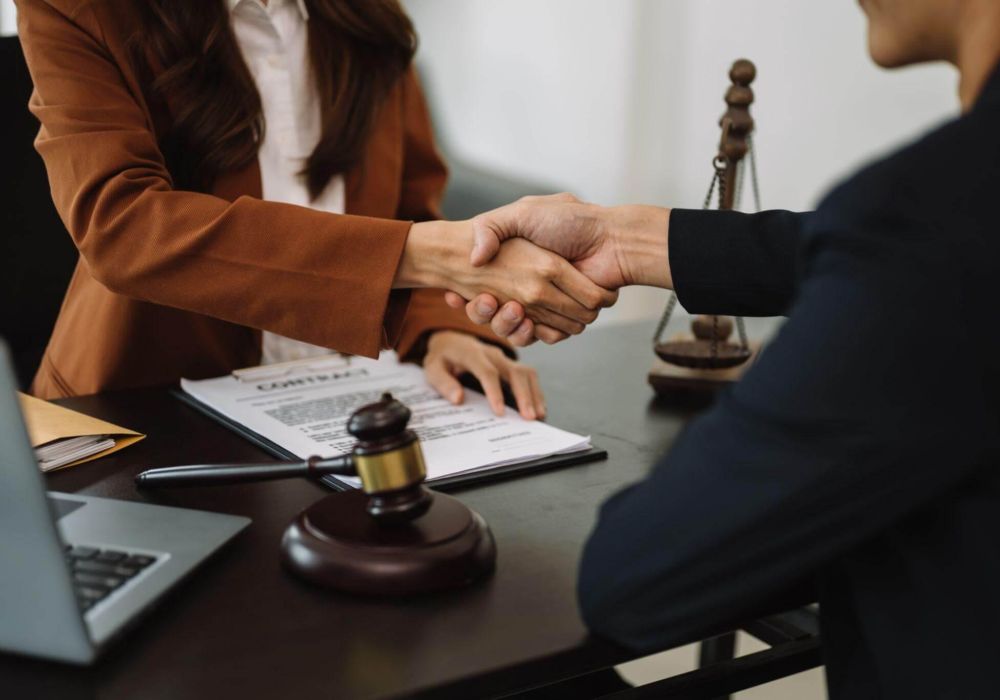 a couple of people shaking hands over a desk