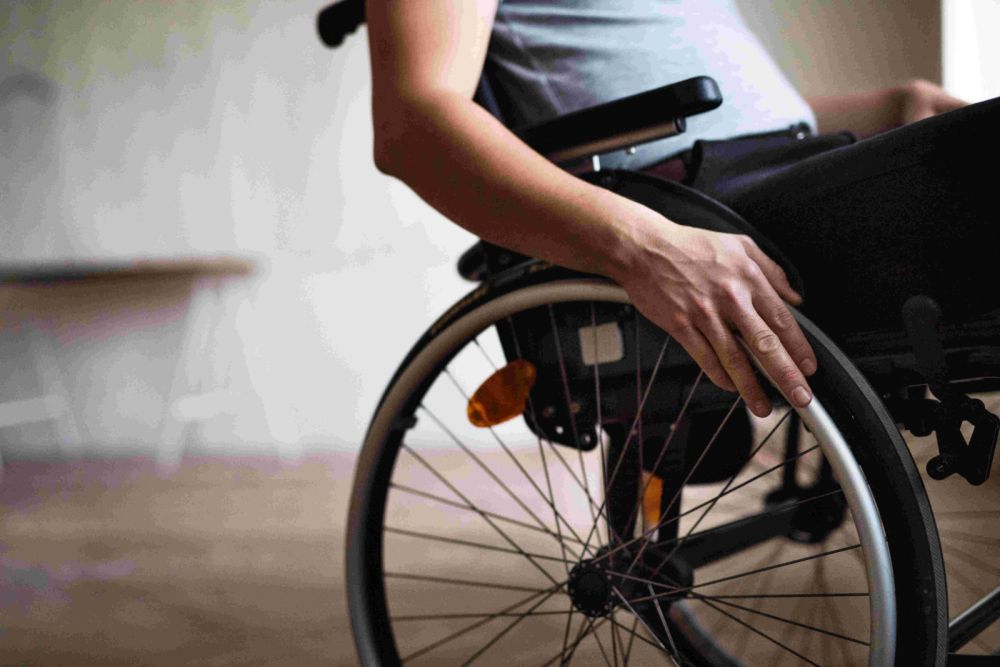 Close-up of a person using a wheelchair, focusing on their hand on the wheel for movement.