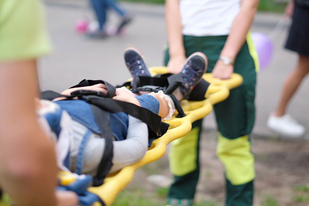 Person being carried on a stretcher by paramedics in a rescue operation, outdoors.