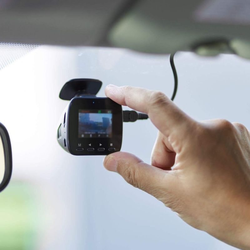 a person holding a camera in their hand that is placed as a dashcam in a car