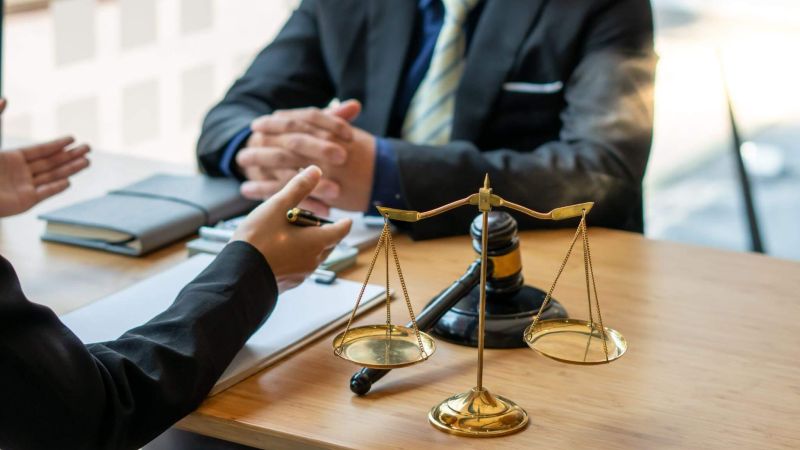 Two people at a table with a scale of justice
