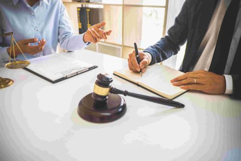 Two professionals discussing legal documents at a table with a gavel and scales; legal and consultancy meeting.