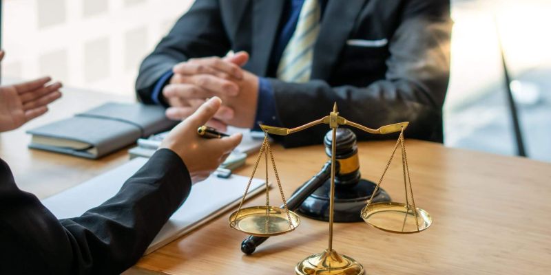 Two people at a table with a scale of justice