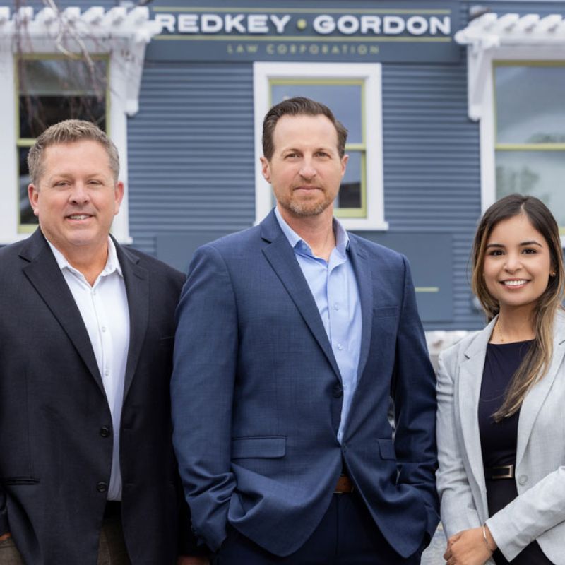 Attorneys from Redkey Gordon Law, wearing business attire, are standing in front of an office building.