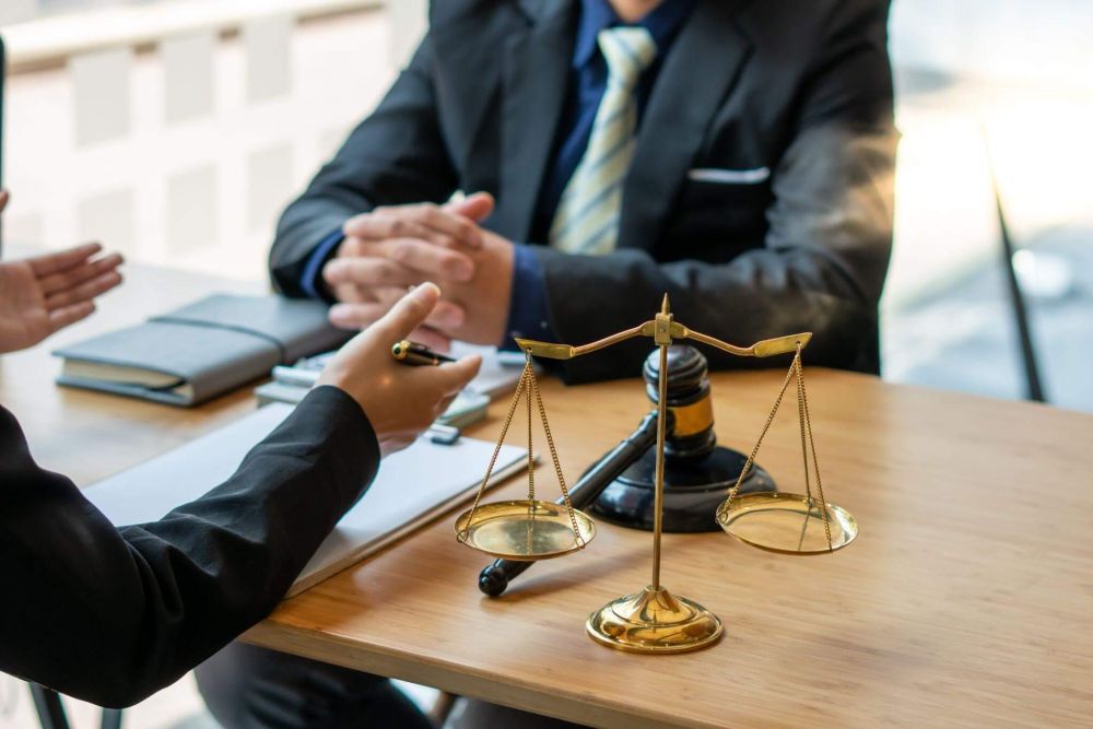 Two people at a table with a scale of justice
