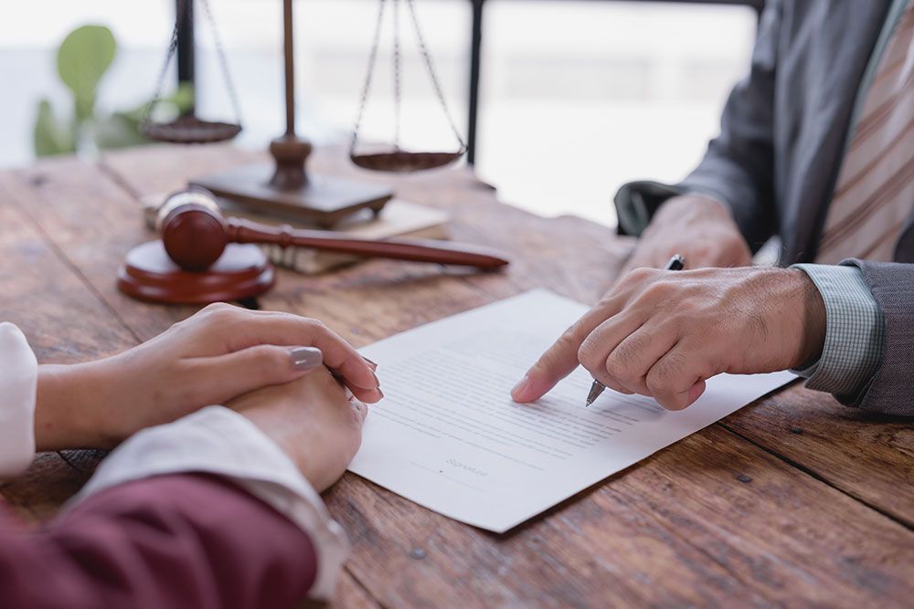 Legal consultation with documents, gavel, and scales on a wooden desk. Attorney advising client, emphasizing agreement details.