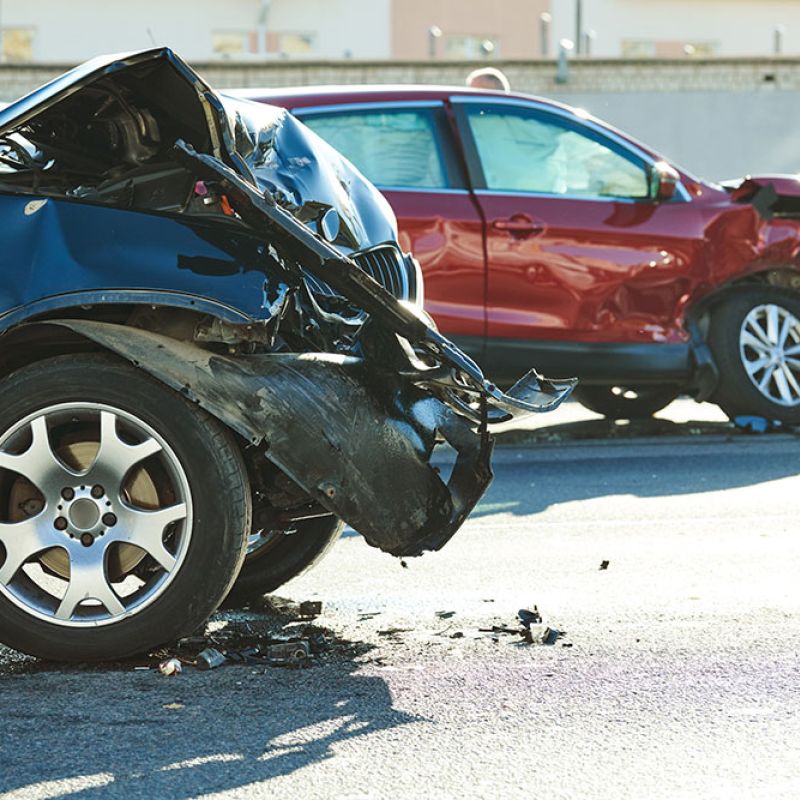 Two cars with severe front-end damage after a collision on a sunny day.