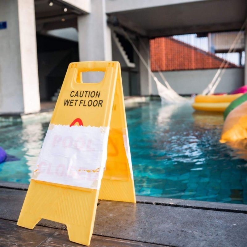 a caution sign next to a swimming pool