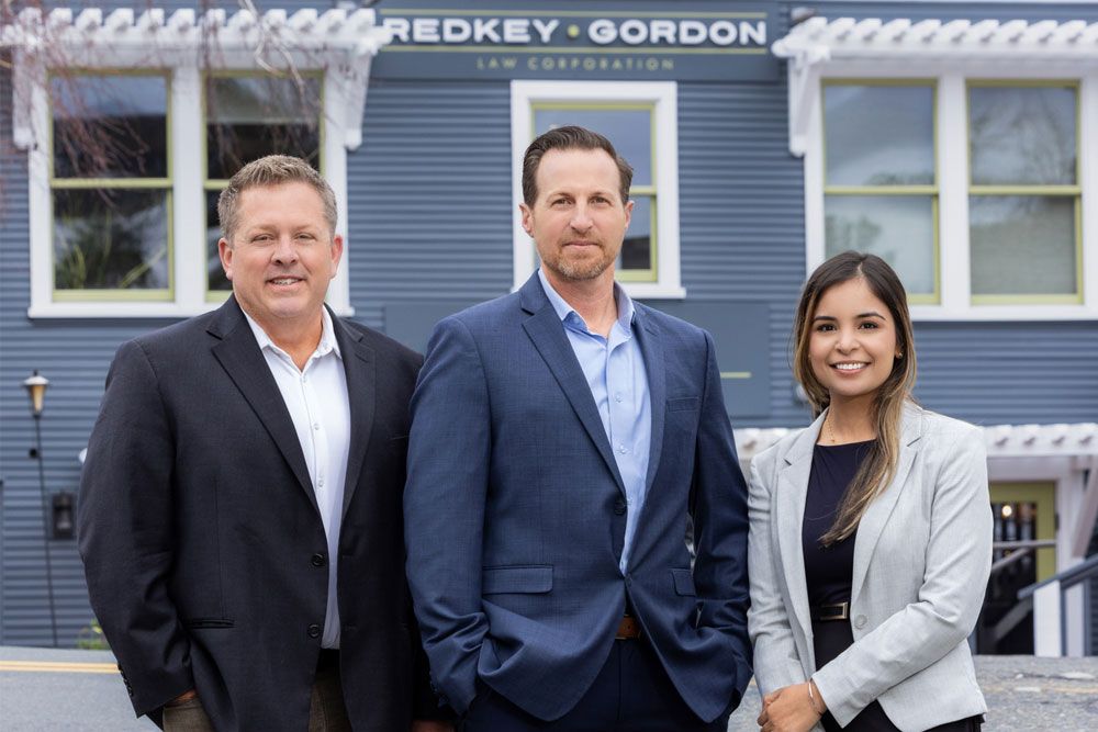 Attorneys from Redkey Gordon Law, wearing business attire, are standing in front of an office building.