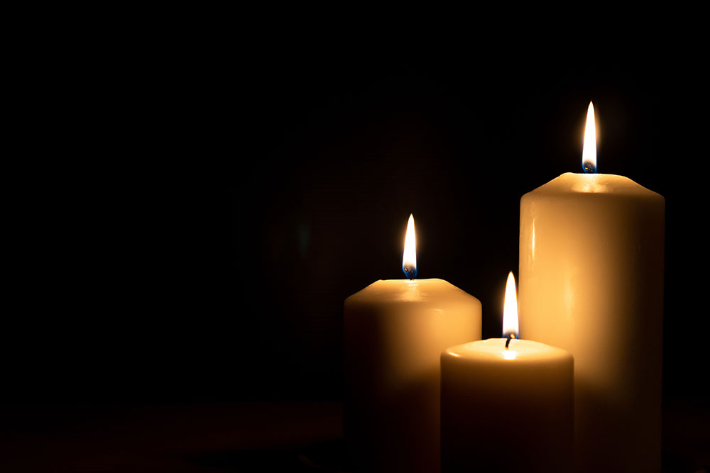 Three lit candles in the dark providing a warm glow, symbolizing tranquility and focus.
