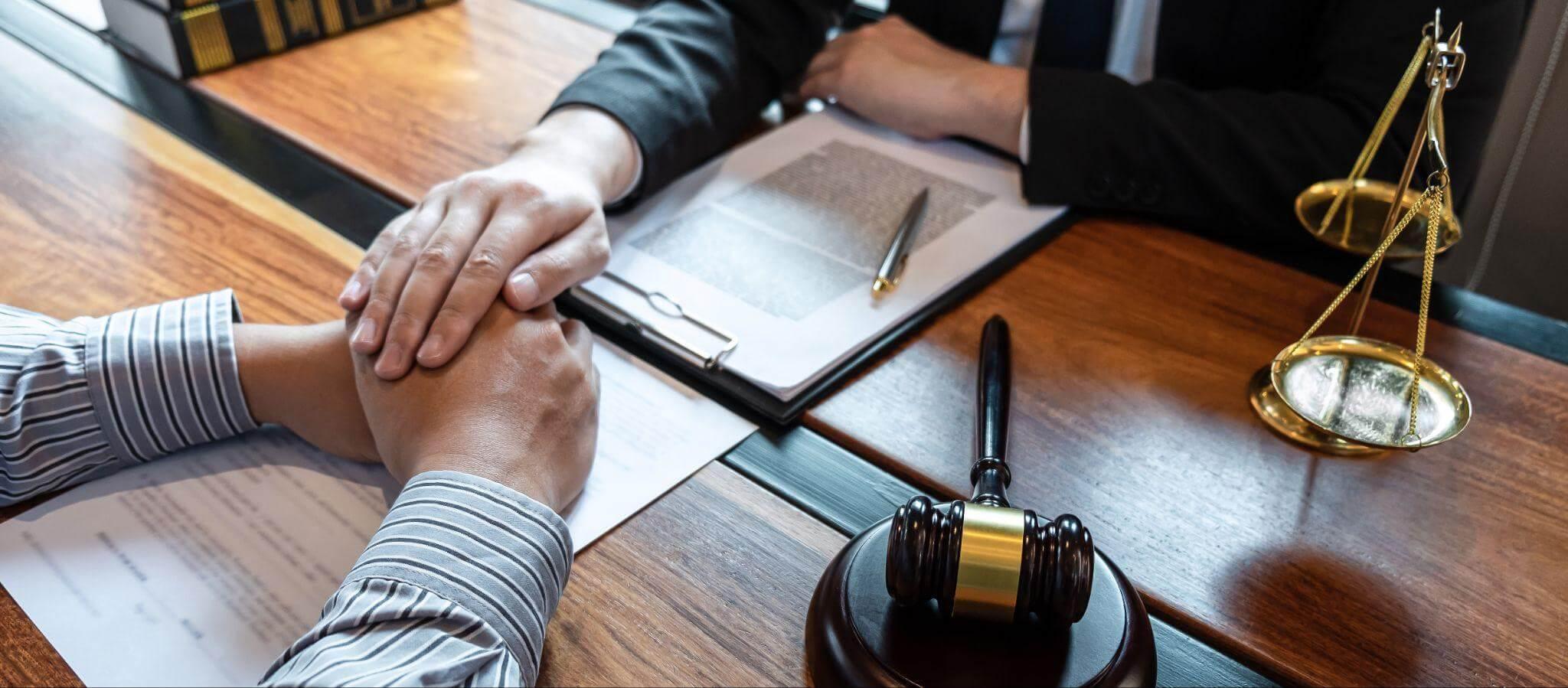 a couple of people having a conversation in a judge's office; one person places his hand on top of the other person's hand to give reassurance