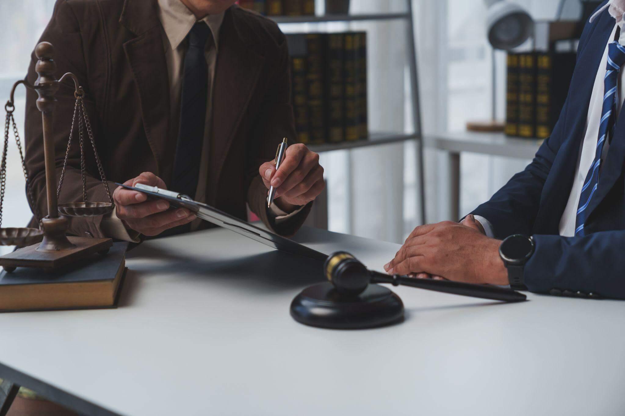two people sitting at a table with a scale of justice on it