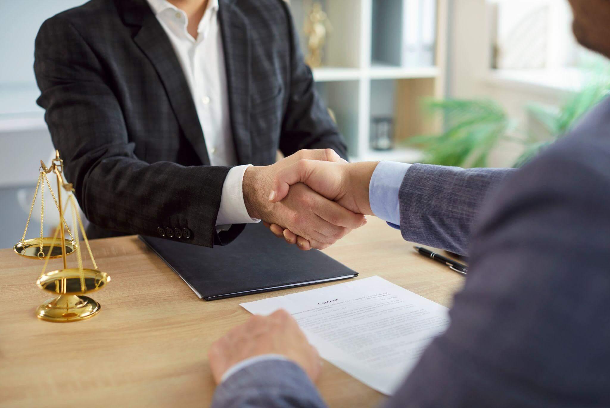 Two men shaking hands at a desk during a