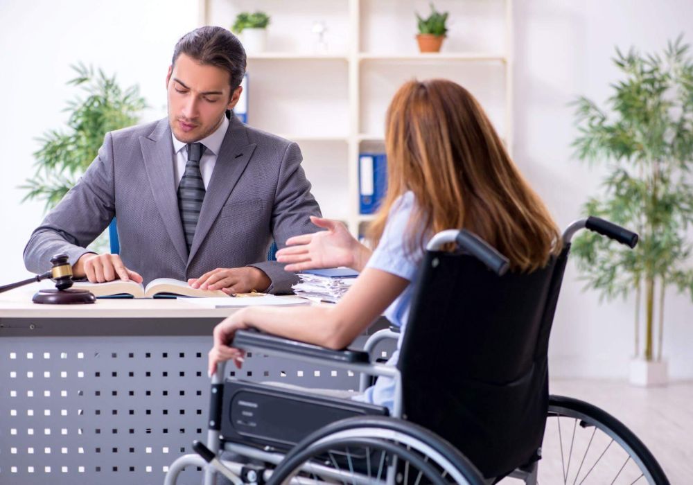 a man in a suit sitting at a desk in front of a woman in a wheelchair
